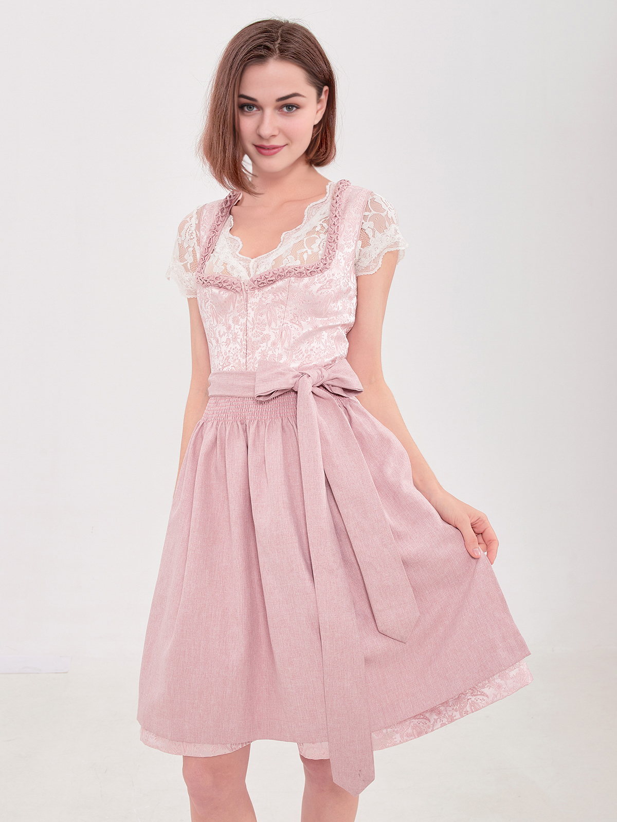 Ein rosa Dirndl mit traditioneller Schürze und Spitzenverzierung